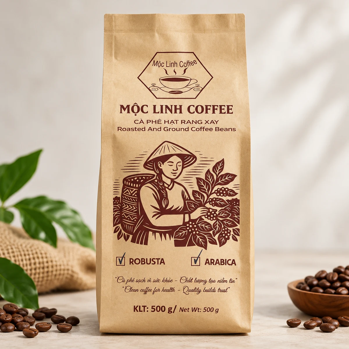 Túi cà phê Mộc Linh Coffee bằng giấy kraft, quy cách 500 g, bên cạnh lá và hạt cà phê
